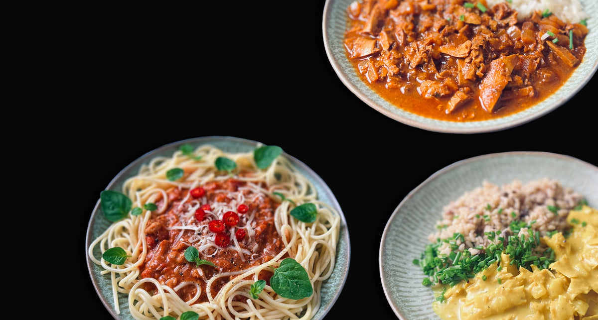 Three plates of prepared plant based dishes arranged on a black background.
